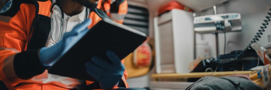 Emergency medical official using a tablet in the back of an ambulance