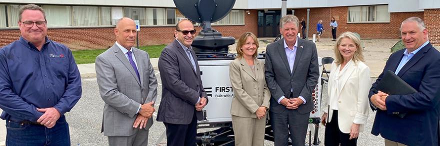 Rhode Island state government, emergency management, FirstNet Authority, and AT&T personnel stand in front of a portable cell site known as a Compact Rapid Deployable.