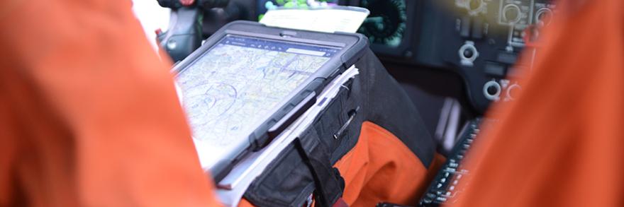 U.S. Coast Guard pilot using tablet, seated in cockpit