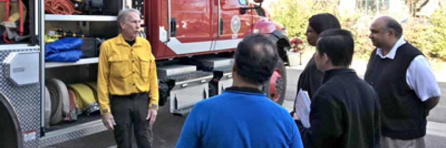 Firefighters talk to a group in front of an attack engine at the FirstNet Lab.