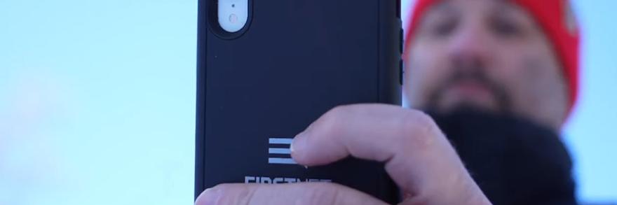 A responder in cold weather gear holds up a FirstNet smartphone