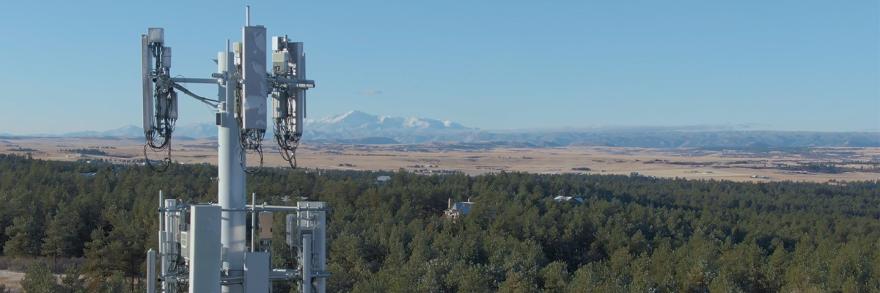 Cellular tower with forest and mountain landscape in backdrop