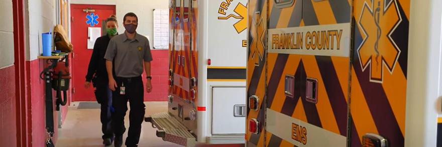 Franklin County EMS personnel walk behind ambulances inside fire station. . 