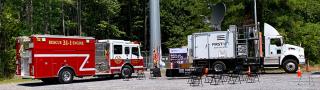 Fire truck and FirstNet Satellite Cell on Light Truck parked in front of a cell tower