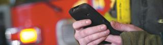Firefighter holds smartphone in front of fire vehicle