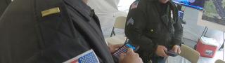 Two officers in uniform look down at FirstNet-enabled devices