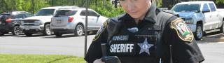 A female Loudon County sheriff in uniform looks down at a phone