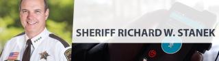 On left, headshot of Sheriff Richard Stanek in uniform, on right, a hand holds a FirstNet device with an app on it