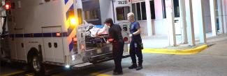 Two paramedics put a patient in the back of an ambulance.