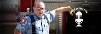 A first responder stands next to an emergency vehicle