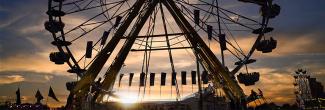 A Ferris wheel backlit by the sunset.