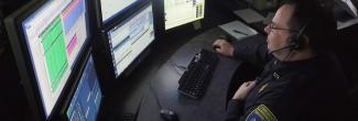 Male dispather viewing a bank of monitors at his desk