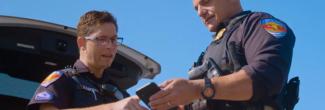 Two Town of Duck officers look at a smartphone 