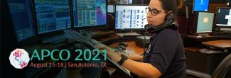 APCO 2021 logo; “APCO 2021; August 15-18|San Antonio, TX”; telecommunicator sits in front of monitors while taking a call.