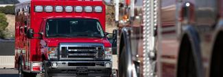 A red ambulance parked behind another public safety vehicle