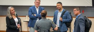 FirstNet Authority staff and Coverage Enhancement Workshop participants, including a uniformed law enforcement officer, stand in a circle speaking