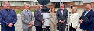 Rhode Island state government, emergency management, FirstNet Authority, and AT&T personnel stand in front of a portable cell site known as a Compact Rapid Deployable.