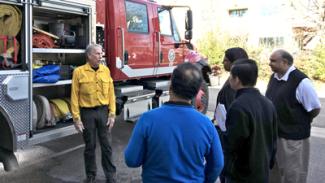 Firefighters talk to a group in front of an attack engine at the FirstNet Lab.