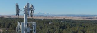 Cellular tower with forest and mountain landscape in backdrop