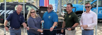 AT&amp;T SE President Joe York, U.S. Representative Kat Cammack, FirstNet Authority Board Chairman Sheriff Adkinson, Dixie County Sheriff Darby Butler, and AT&amp;T President of FirstNet &amp; Public Sector Mobility Scott Agnew standing under a FirstNet by AT&amp;T tent, holding a ribbon and large scissors for a ceremonial event launching a new cell tower in Horseshoe Beach, Florida