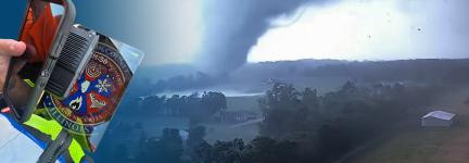 A Marion County Emergency Management official using a FirstNet enabled cell phone and tablet; an EF4 tornado touching down in Marion, Illinois in 2005.