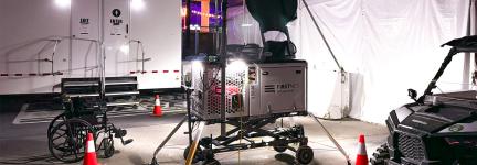 A FirstNet Compact Rapid Deployable set up near medical tents at the Electric Daisy Carnival. Trailer, wheelchair, side-by-side vehicle, and orange cones.